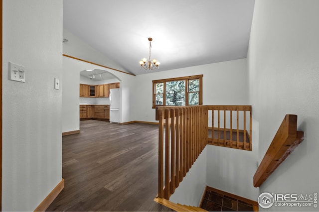 staircase with visible vents, arched walkways, baseboards, wood finished floors, and vaulted ceiling