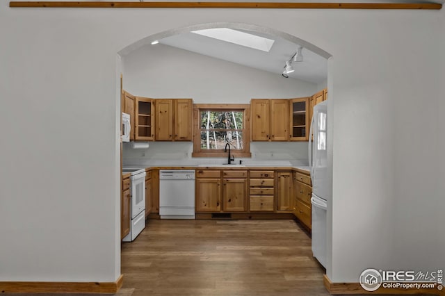 kitchen with light countertops, a sink, lofted ceiling, and white appliances