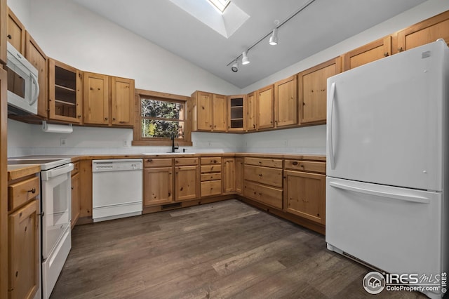 kitchen featuring track lighting, a sink, vaulted ceiling with skylight, white appliances, and light countertops