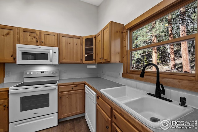 kitchen featuring a sink, glass insert cabinets, white appliances, and a healthy amount of sunlight