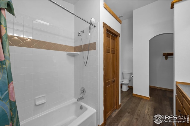 bathroom featuring vanity, wood finished floors, toilet, baseboards, and shower / tub combo
