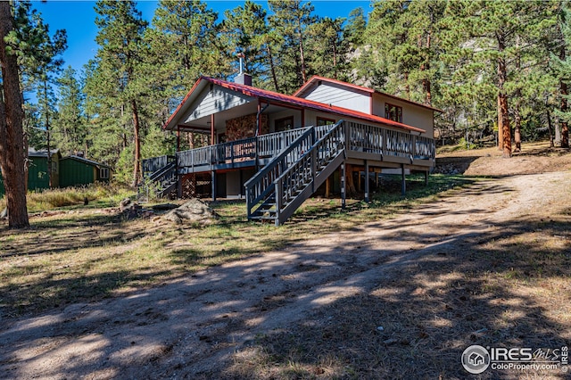 view of front of home featuring a wooden deck, stairs, and a chimney
