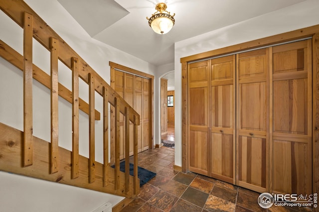 entrance foyer featuring baseboards, arched walkways, and stone tile floors