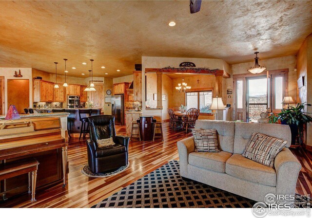 living area with dark wood-style floors, a textured ceiling, a notable chandelier, and recessed lighting