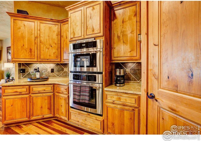 kitchen with double oven, brown cabinetry, and decorative backsplash