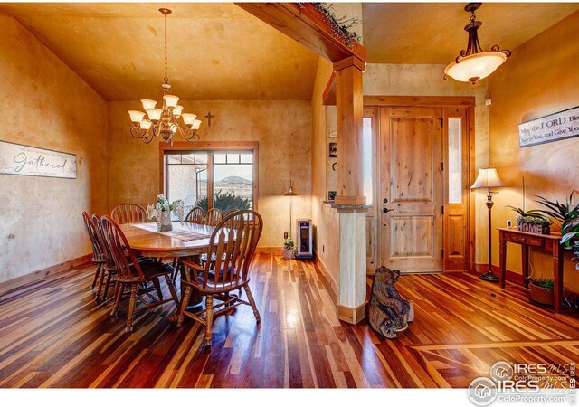 dining space with wood-type flooring, baseboards, and an inviting chandelier