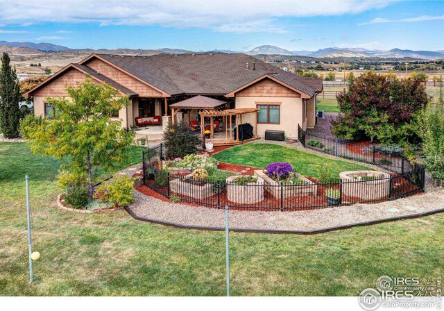 view of front facade featuring central AC unit, a patio, a fenced backyard, a mountain view, and a front lawn