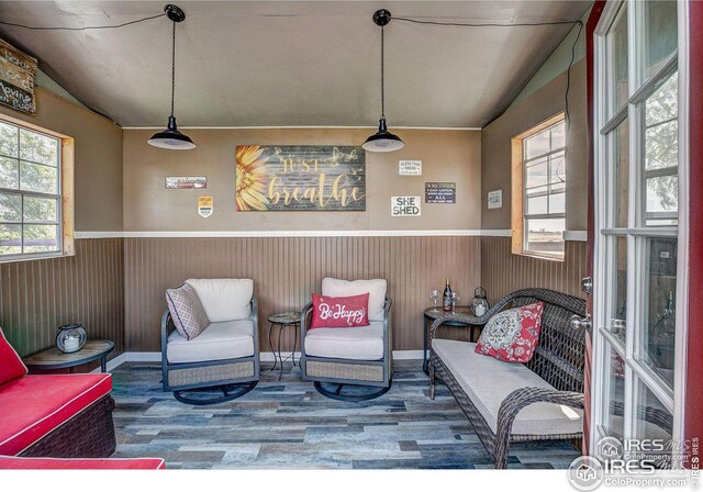 living area featuring a wainscoted wall, wood finished floors, lofted ceiling, and wooden walls