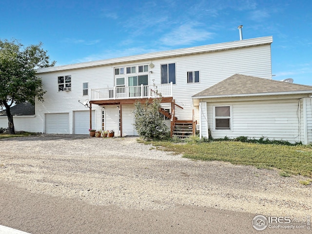 view of front of property featuring roof with shingles, stairs, an attached garage, a deck, and driveway
