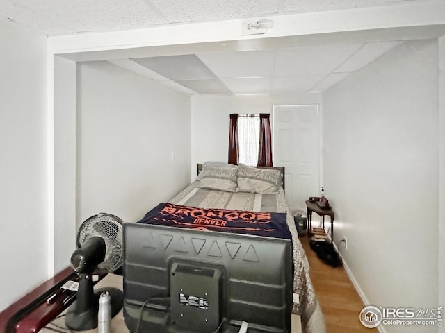 bedroom featuring baseboards, a paneled ceiling, and wood finished floors