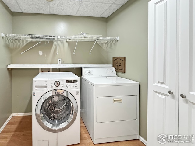 clothes washing area featuring baseboards, separate washer and dryer, laundry area, and wood finished floors