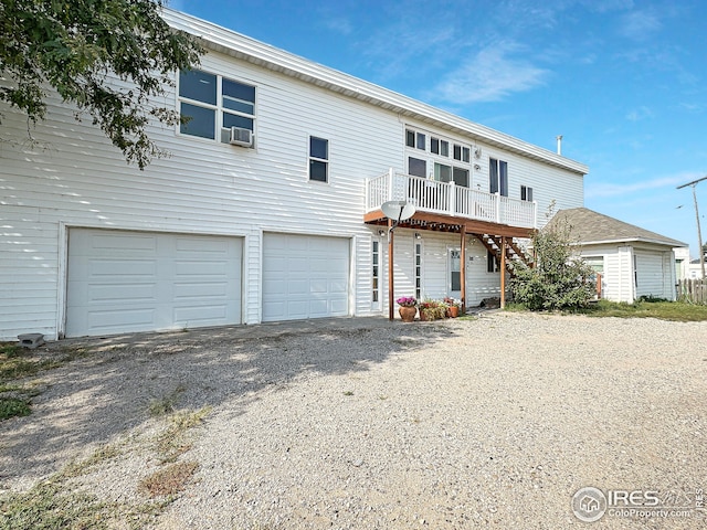 view of front of home featuring a garage, gravel driveway, cooling unit, a deck, and stairway