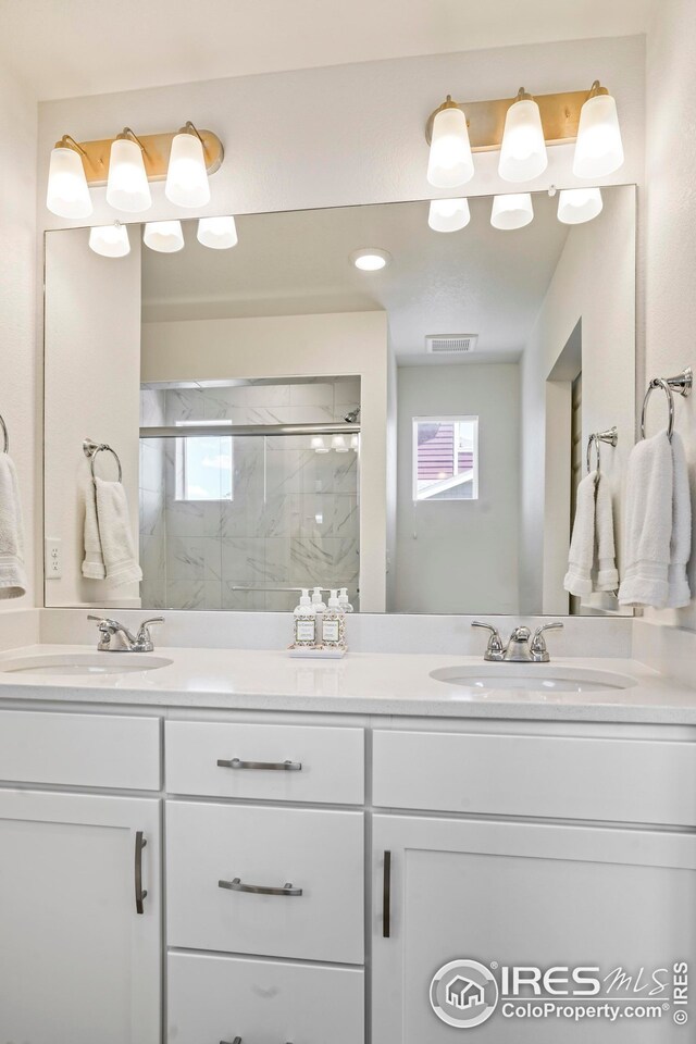 bathroom featuring a shower with door and vanity