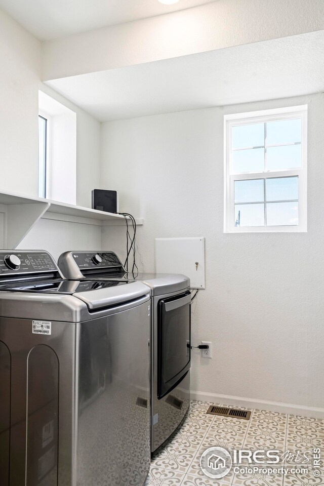 laundry area with light tile patterned floors and independent washer and dryer