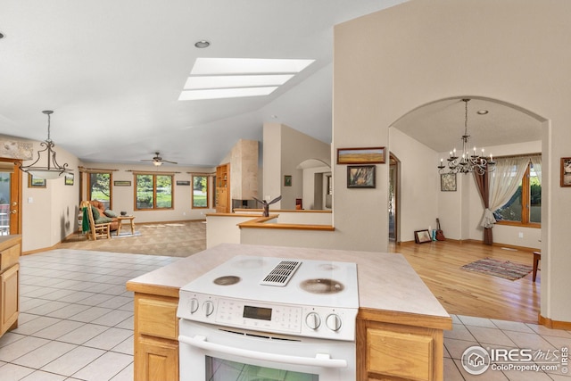 kitchen featuring light tile patterned flooring, ceiling fan with notable chandelier, hanging light fixtures, and electric stove