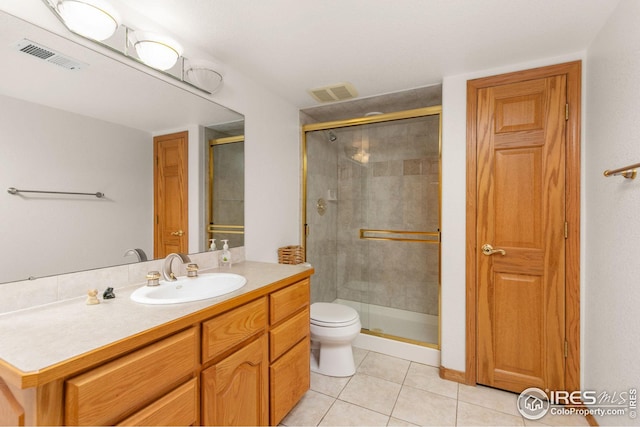 bathroom featuring tile patterned flooring, vanity, toilet, and a shower with door