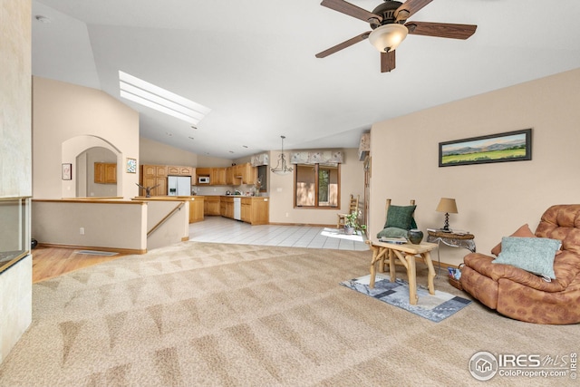 living room with ceiling fan, light colored carpet, and lofted ceiling with skylight