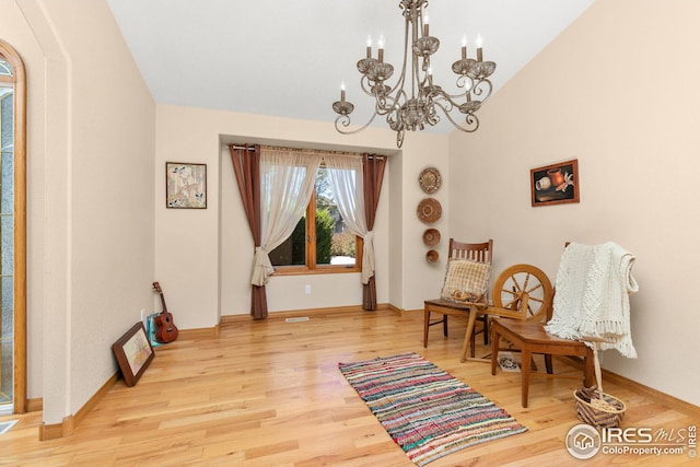 sitting room with light hardwood / wood-style flooring, lofted ceiling, and a notable chandelier