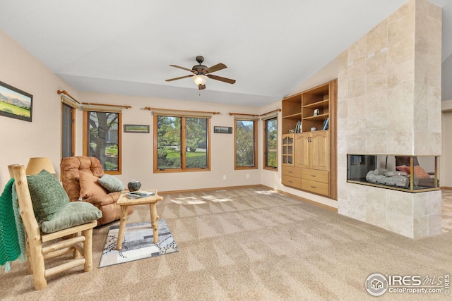 carpeted living room featuring a fireplace, vaulted ceiling, and ceiling fan