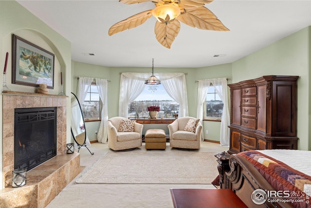 bedroom featuring ceiling fan, a tile fireplace, and multiple windows