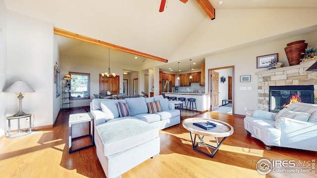 living room with a stone fireplace, light hardwood / wood-style flooring, and beam ceiling