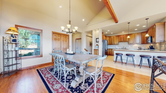 dining room with high vaulted ceiling, light wood-type flooring, a notable chandelier, and sink