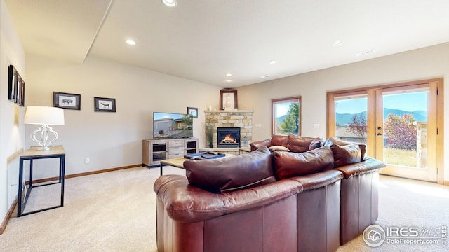 carpeted living room with french doors and a stone fireplace