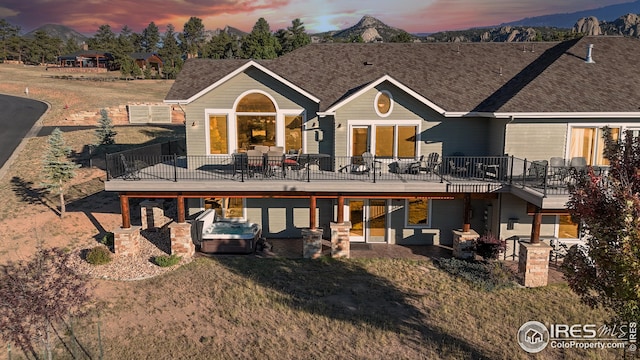 back house at dusk featuring a wooden deck and a patio area