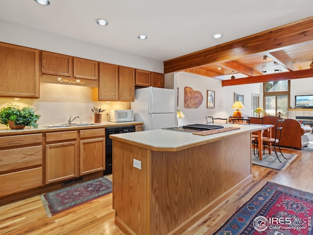 kitchen with sink, beamed ceiling, light hardwood / wood-style floors, white appliances, and a kitchen island