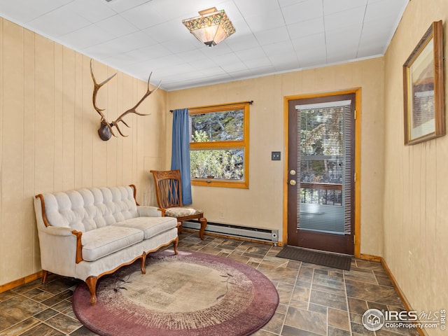 living area featuring a baseboard radiator, stone finish flooring, wood walls, and baseboards