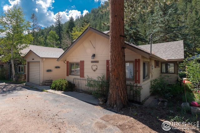 view of front of house with a shingled roof, driveway, and a garage