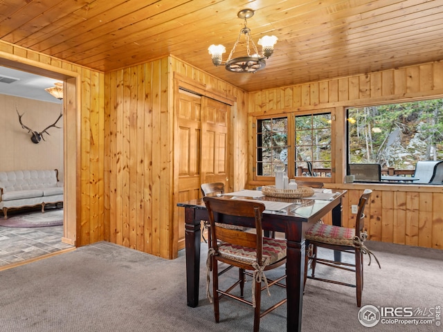 dining area featuring a chandelier, carpet floors, wood walls, and wood ceiling