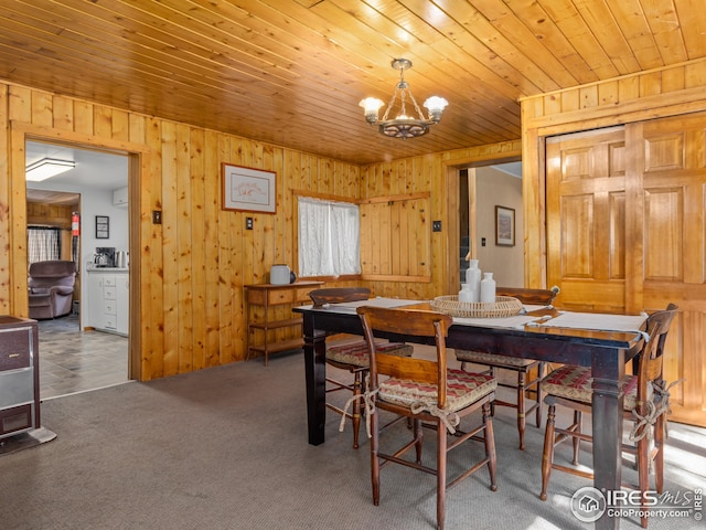 carpeted dining room with wooden ceiling, a notable chandelier, and wooden walls