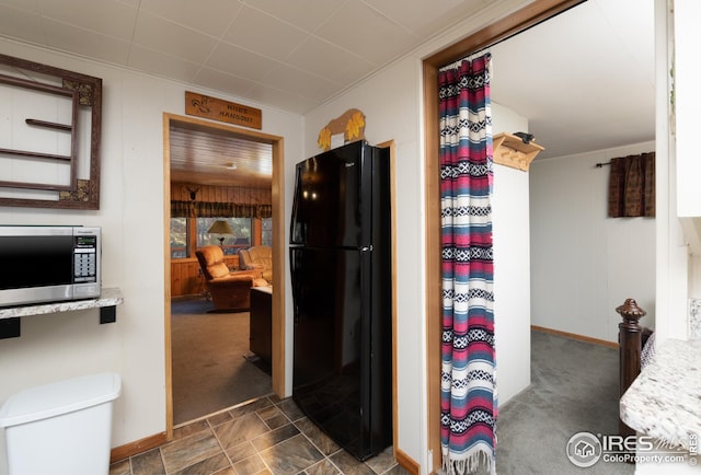 kitchen featuring stainless steel microwave, carpet, freestanding refrigerator, and baseboards