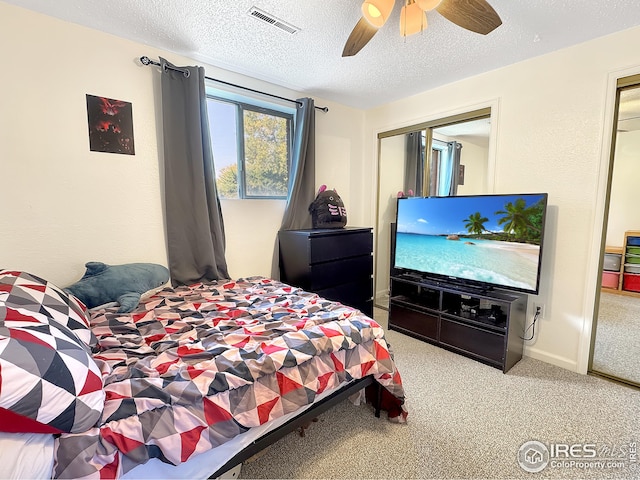 carpeted bedroom with ceiling fan, a textured ceiling, and a closet