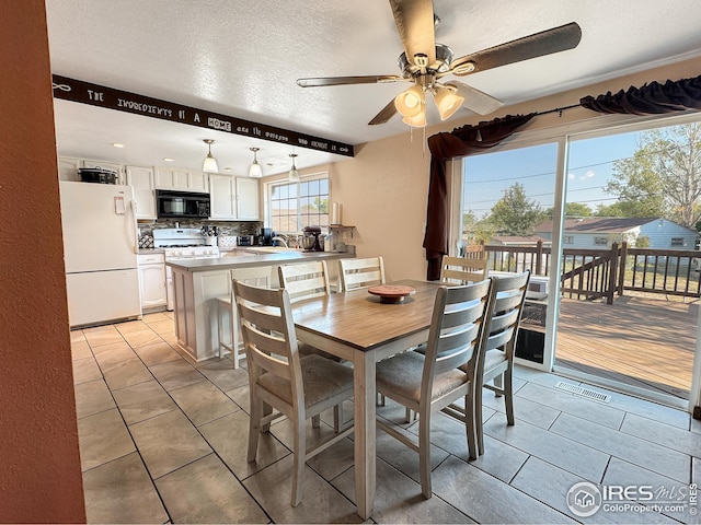 dining area with ceiling fan, sink, light tile patterned floors, and a textured ceiling