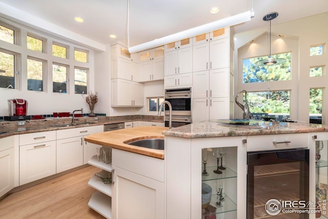 kitchen featuring white cabinetry, beverage cooler, stainless steel double oven, and a sink