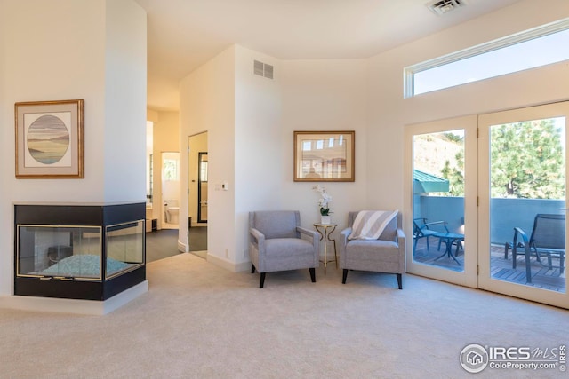 sitting room featuring visible vents, carpet floors, and a towering ceiling