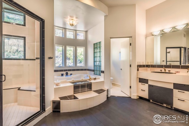 bathroom featuring a shower stall, vanity, toilet, a garden tub, and wood finished floors