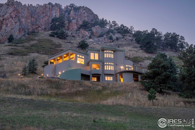 view of front of home with stucco siding, a balcony, and a mountain view