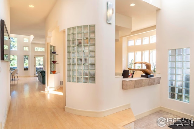 hall with recessed lighting, a high ceiling, hardwood / wood-style floors, and baseboards