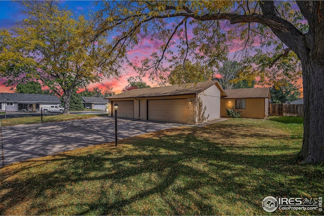 single story home featuring a garage and a lawn