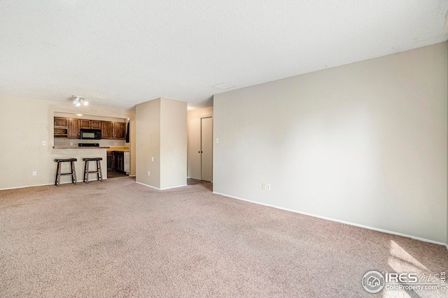 unfurnished living room with light colored carpet and a textured ceiling