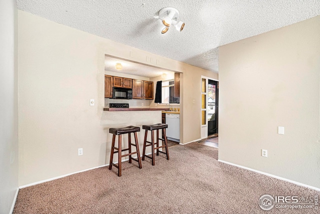 kitchen featuring kitchen peninsula, light colored carpet, a breakfast bar area, and dishwasher