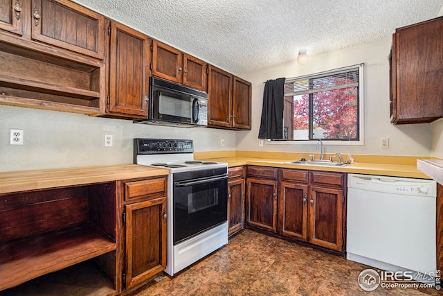 kitchen featuring white appliances, sink, and a textured ceiling