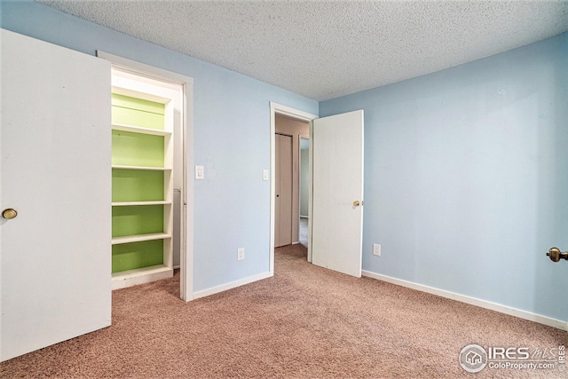 unfurnished bedroom with carpet floors, a textured ceiling, and a walk in closet