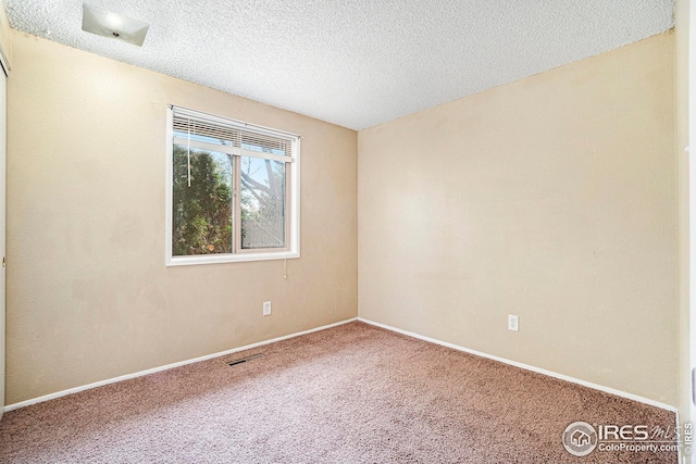 carpeted empty room with a textured ceiling