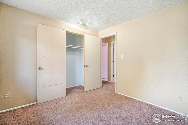 unfurnished bedroom featuring light colored carpet, a textured ceiling, and a closet