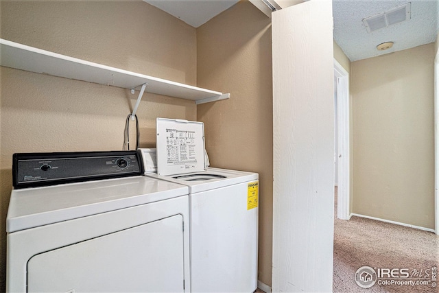 washroom featuring light carpet, separate washer and dryer, and a textured ceiling