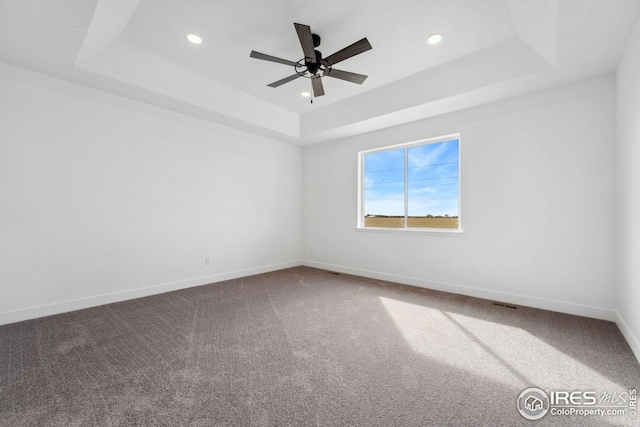 spare room with a raised ceiling, carpet flooring, recessed lighting, and baseboards